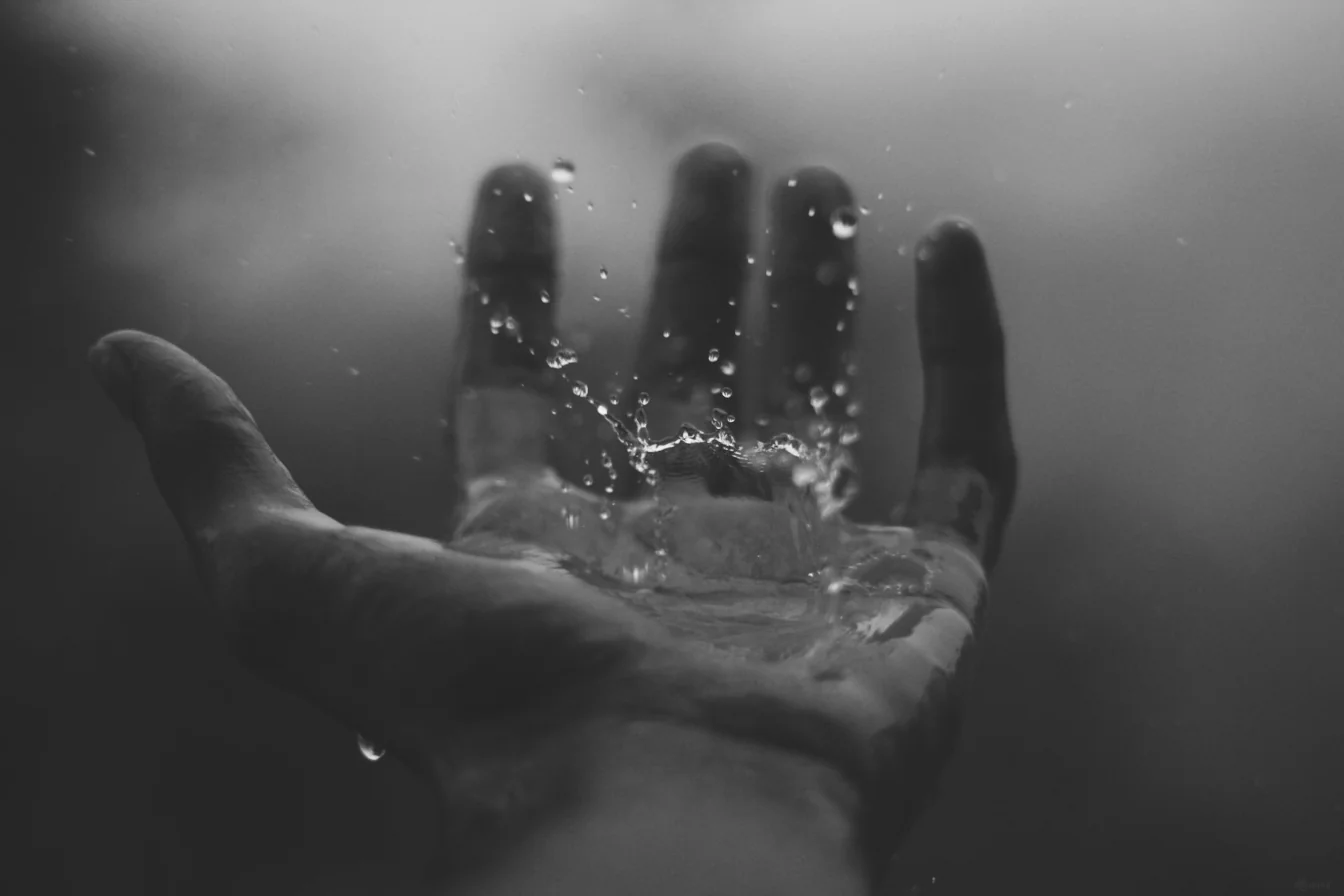 Hand with palm up and water drop falling on the persons hand.