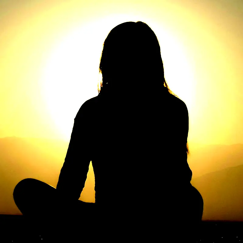 Sunset with the silhouette of a person meditating. 